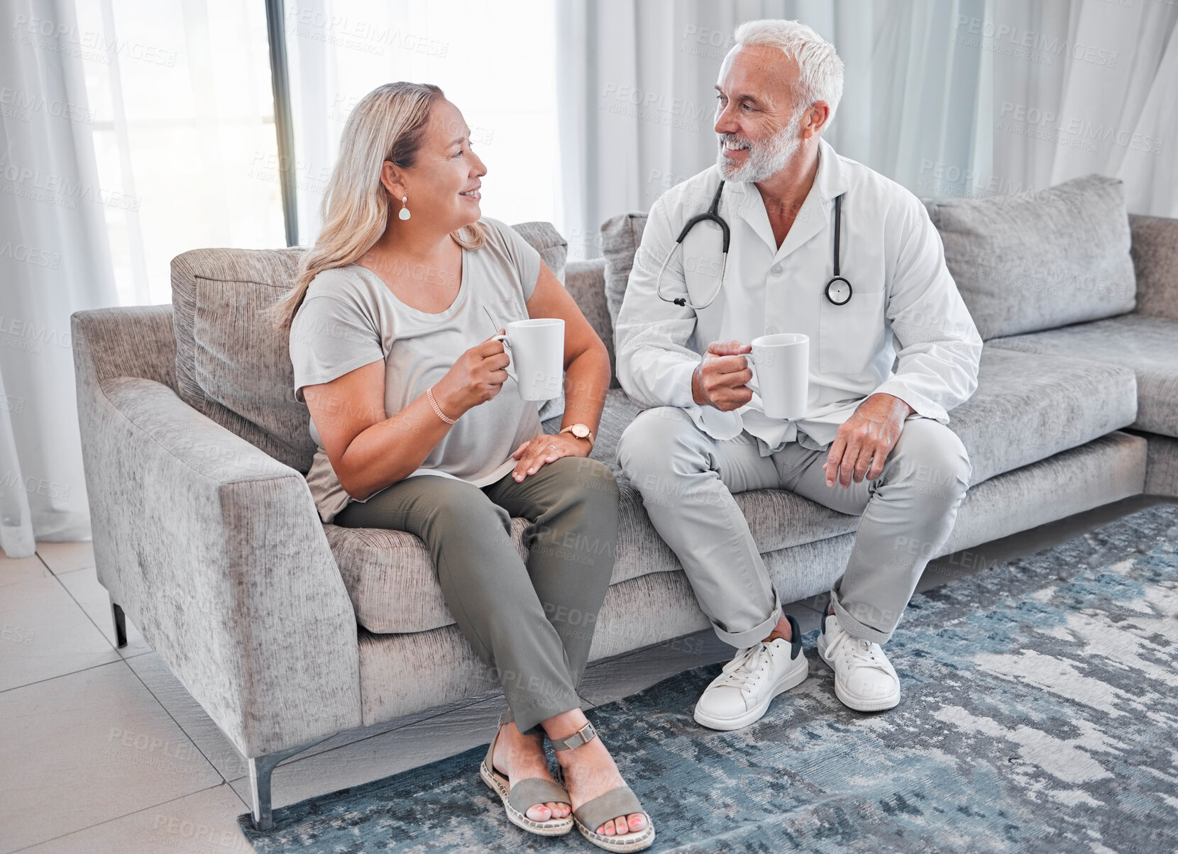 Buy stock photo Home visit, doctor and woman on sofa talking and drinking coffee in living room after consulting. Healthcare, medicine and a medical professional man and lady on couch in house or apartment with tea.