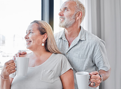 Buy stock photo Elderly couple, hug and coffee by window with smile in contemplation, vision or morning routine at home. Happy senior man and woman smiling looking out glass while enjoying a warm drink together