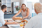 Lunch, celebration and happy family with food at a dining room table on holiday at the accommodation. Serving, dinner and senior woman with bread and chicken for hungry people in family home