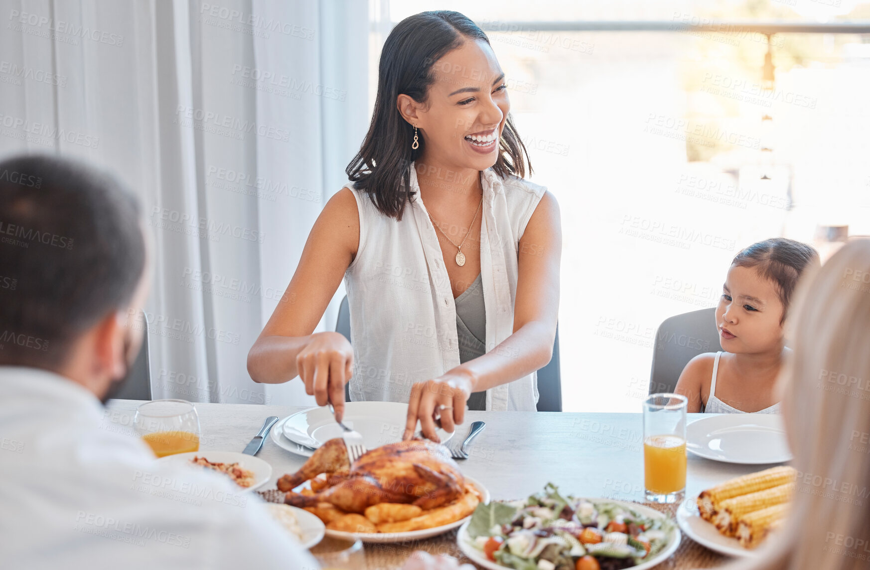 Buy stock photo Chicken, happy and family lunch with woman cutting with knife, meal and food in dining room or celebration event. Love, happiness and group of people eating or laugh at brunch in family home together