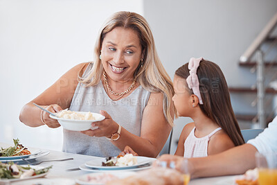 Buy stock photo Happy, lunch and grandmother with child at the table eating a meal together with their family. Happiness, conversation and senior woman talking, eating and bonding at dinner, party or event at a home