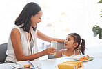 Woman, food and eating at home for health, wellness and diet nutrition at the dining table. Meal, lunch and mother and daughter eat and drink juice together for hungry child in the family home