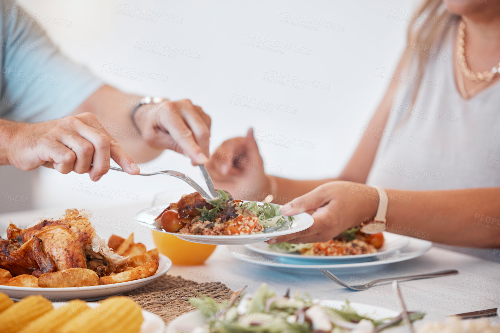 Buy stock photo Hands, food and utensils with a couple eating a meal together at a dinner table in their home. Hand, roast and hungry with a man and woman enjoying lunch or dinner while bonding in a house closeup