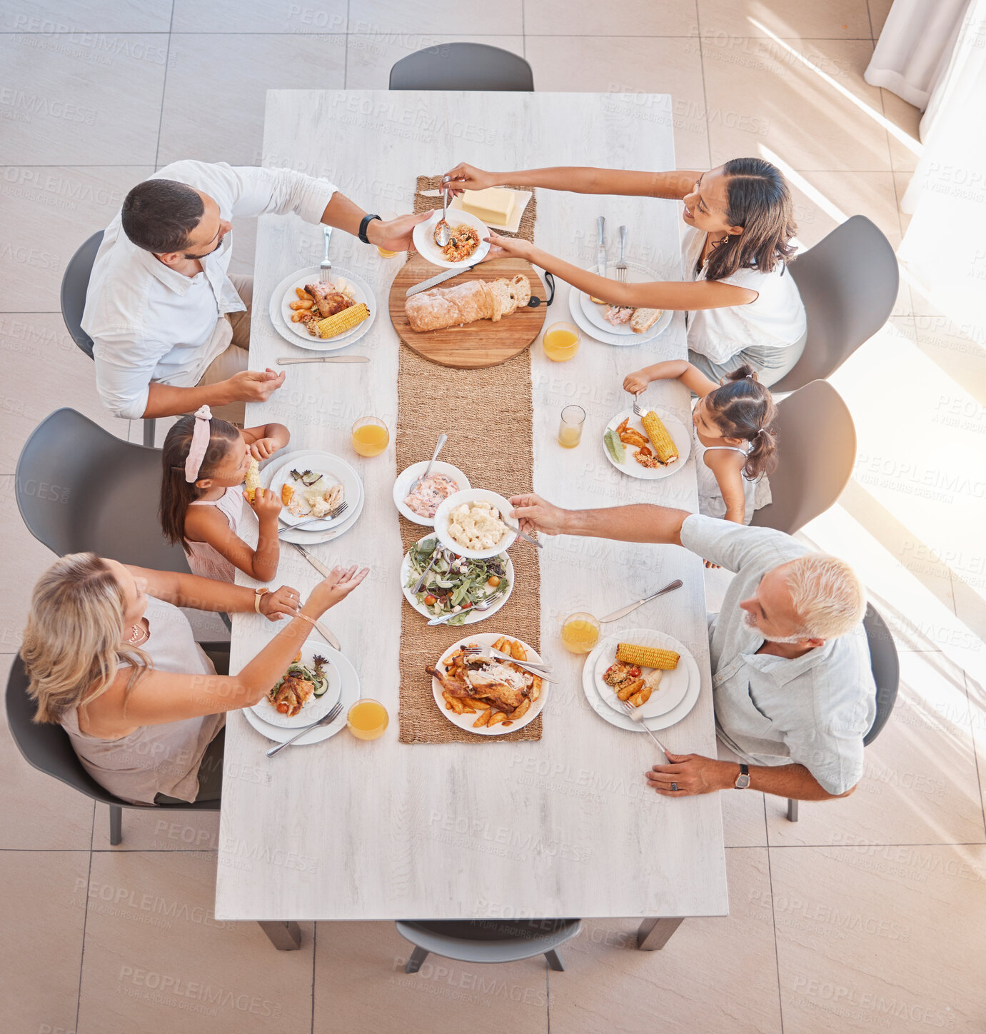 Buy stock photo Family, food and lunch with love and care at the dining room table to eat and drink. Group, grandparents and parents with kids eating a delicious meal in a family home with a happy family in top view