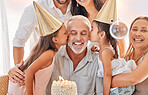 Family, birthday and girls kiss grandfather at home in celebration. Big family, cake and kids kissing grandpa with grandma, mother and father celebrating, having fun and enjoying party time together.