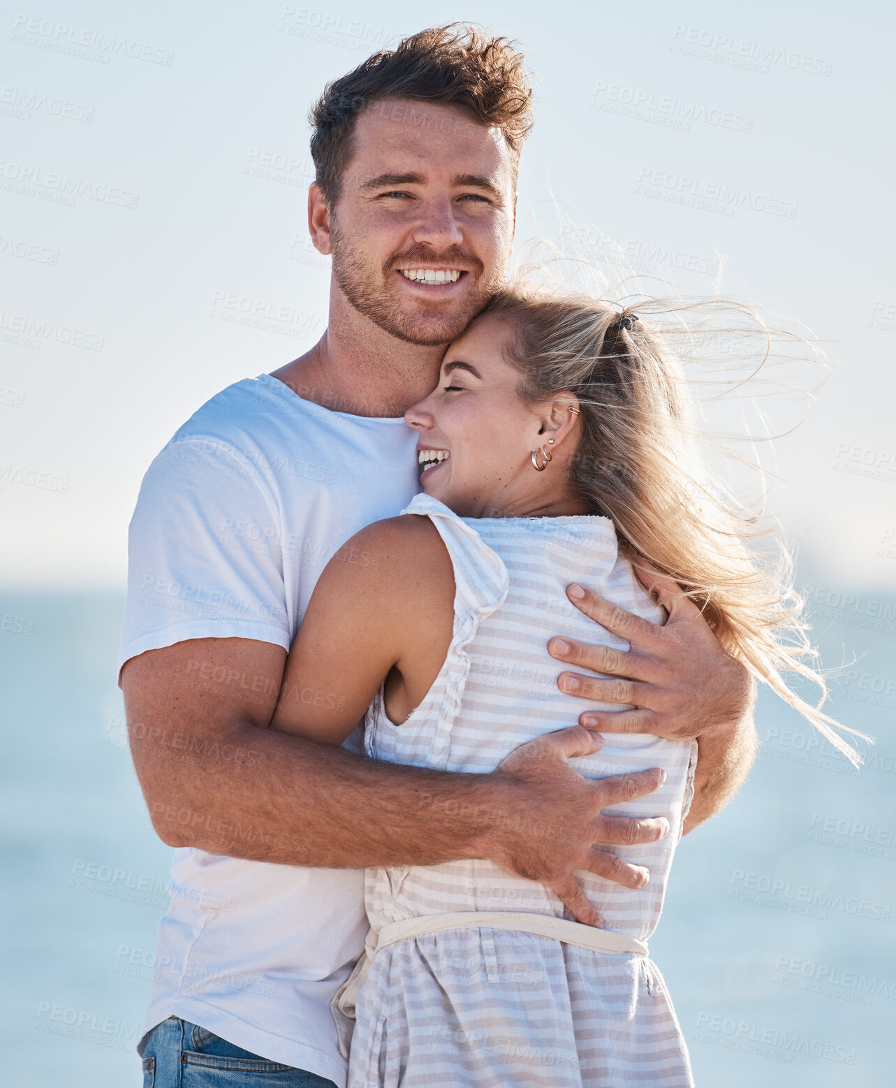 Buy stock photo Love, beach hug and couple smile on romantic ocean holiday trip together for relationship bonding, romance and peace. Face of happy man, woman with a smile and nature summer water vacation by the sea