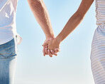 Couple holding hands, blue sky and love together in nature, summer vacation and outdoor for save the date marriage relationship. Closeup hands of man, woman and travel in sunshine, relax and walking 