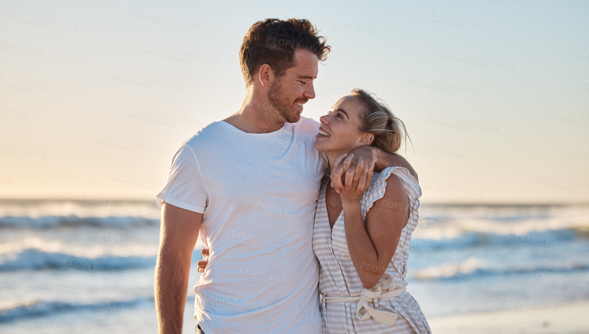 Buy stock photo Sunset beach, love and summer with a couple hug on the sand by the sea or ocean while on holiday together. Happy, smile and romance with man and woman bonding while on travel vacation or break at sea