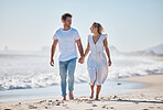 Couple, beach and holding hands for love, walk or care in relationship bonding together in the outdoors. Happy man and woman walking in romance while enjoying summer vacation on the sandy ocean coast