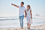 Couple, beach and travel holiday, love and happy smile, anniversary and date while walking, holding hands and point. Man, woman and summer vacation, happiness and together in nature and marriage life