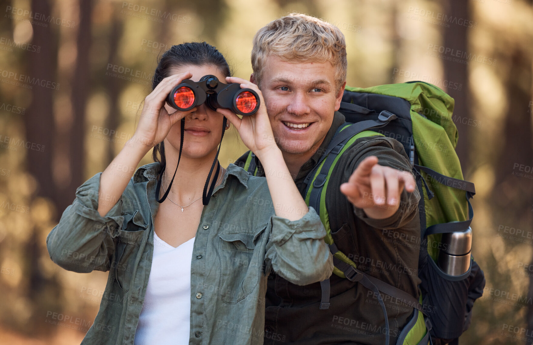 Buy stock photo Couple, binoculars and pointing while hiking in nature, travel or outdoors vacation, holiday or trip. Freedom, man and woman on adventure, sightseeing or trekking and looking with field glasses.

