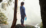 Hiking, mountain and forest woman with fitness goal, adventure and journey challenge achievement on rock or hill in winter. Sports, athlete and trekking person with water bottle walking in the woods