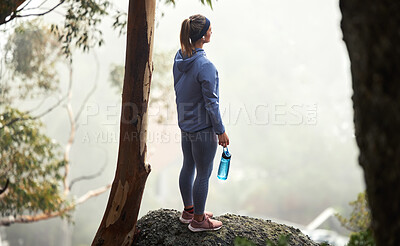 Buy stock photo Hiking, mountain and forest woman with fitness goal, adventure and journey challenge achievement on rock or hill in winter. Sports, athlete and trekking person with water bottle walking in the woods