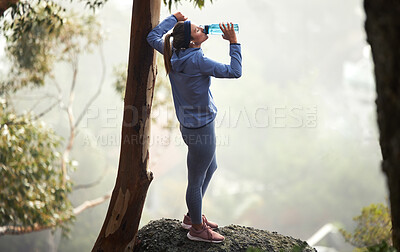 Buy stock photo Hiking, woman and drinking water in nature, forest and mountain for healthy lifestyle, wellness and outdoor adventure. Young girl, water bottle and trekking, mountains and freedom, relax and travel 