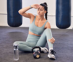 Fitness, tired and woman with burnout or headache, break and relax after workout in gym, water bottle and kettlebell for weightlifting. Bodybuilder, exercise and exhausted from sports and cardio.