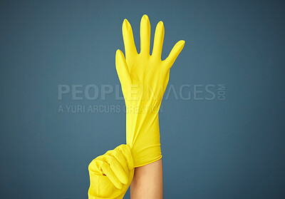 Buy stock photo Cleaning, yellow rubber glove and hand on studio background for cleaner, hygiene and spring cleaning mockup on blue background. Hand of woman in uniform for housekeeping and cleaning service mock up