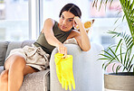 Tired, woman and cleaning of a woman with gloves feeling fatigue in a house living room sofa. Portrait of a young person spring cleaning a home lounge feeling bored and frustrated on a couch