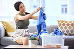 Cleaning, laundry and folding clothes with woman in living room for housekeeping, fresh and tidy. Fabric, washing and basket of linen with cleaner on sofa at home for household, chores and domestic 