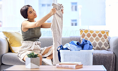 Buy stock photo Laundry, housekeeping and woman folding clothes, cleaning and working in the living room of her house. Routine, washing and cleaner with clean clothing in a basket on the sofa of the home lounge