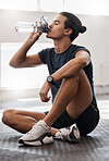 Water bottle, fitness and gym man tired after a fitness training, exercise challenge and wellness goal with healthy diet or nutrition. Young sports person floor drinking water for healthy lifestyle