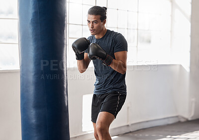 Buy stock photo Man, boxing and training with punching bag in gym for body fitness, health and wellness with boxing gloves. Boxer, martial arts or exercise workout for sport, cardio or focus with precision in studio