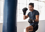 Fitness, boxing and man training for a fight competition, workout or match with a boxing bag in the gym. Sports, motivation and athlete boxer doing MMA exercise to practice in fighting dojo or studio