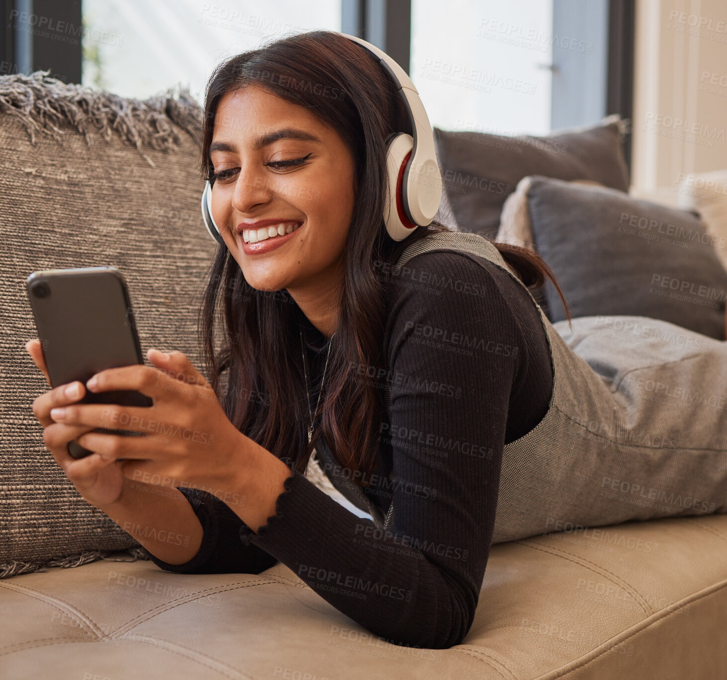 Buy stock photo Woman, phone and headphones for listening to music online for happiness, calm and peace while streaming on audio app on home and living room sofa. Female watching video or movie on internet with 5g