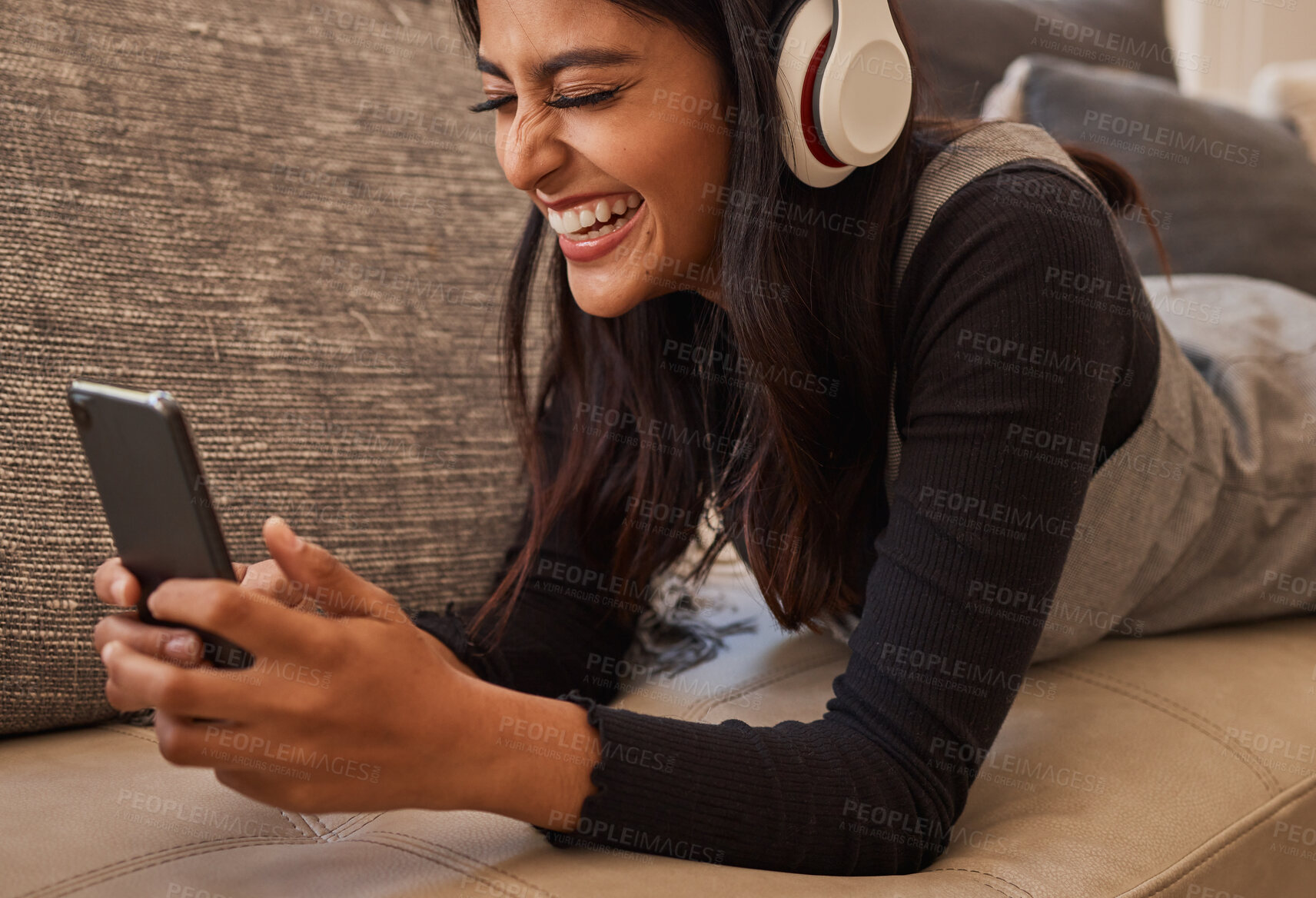 Buy stock photo Smartphone, headphones and woman on sofa listening to music, watch online video chat or mobile app zoom call. Excited, relax and music of a youth girl audio, podcast or online subscription streaming