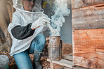 Beekeeper, bee suit and smoke, fog and smoking a beehive box outdoor on a farm, working and safety protection. Agriculture work, senior woman and farmer with a smoker to extract honey or honeycomb