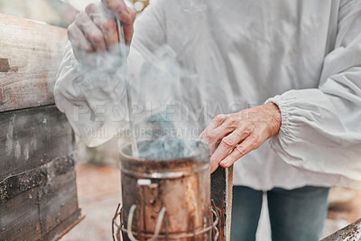 Buy stock photo Hands, smoker fire and beekeeper on farm mix and refueling with tool. Safety, beekeeping and worker in suit preparing smoking pot or equipment to calm or relax bees, beehive or bugs for honey harvest