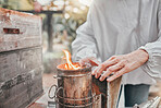 Beekeeper, bee bellows and fire to smoke in closeup at apiary in farming, agriculture and industry. Beekeeping, woman working and hands zoom with flame for bees, safety and farm for honey production