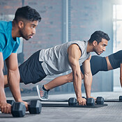 Group, workout and dumbbell push up at gym for muscle, power or strength.  Teamwork, sports or energy of people, athletes or bodybuilder friends  exercise or training at fitness center for healthcare. Stock