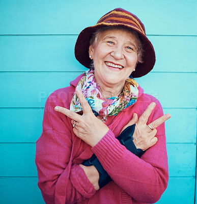 Buy stock photo Peace sign, hip hop and portrait of a senior woman in the city with energy, smile and urban fashion. Cool, trendy and elderly grandma with emoji hand in retirement on a blue background or wall