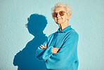 Fashion, sunglasses and portrait of old woman with arms crossed on wall background for stylish, cool and unique aesthetic. Retirement, beauty and elderly female model with designer brand glasses.