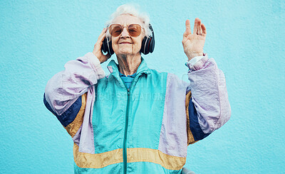 Buy stock photo Happy, elderly and woman with headphone music for wellness, fun and retirement leisure. Urban, retro and funky senior person listening to feel good streaming on headphones at blue wall.

