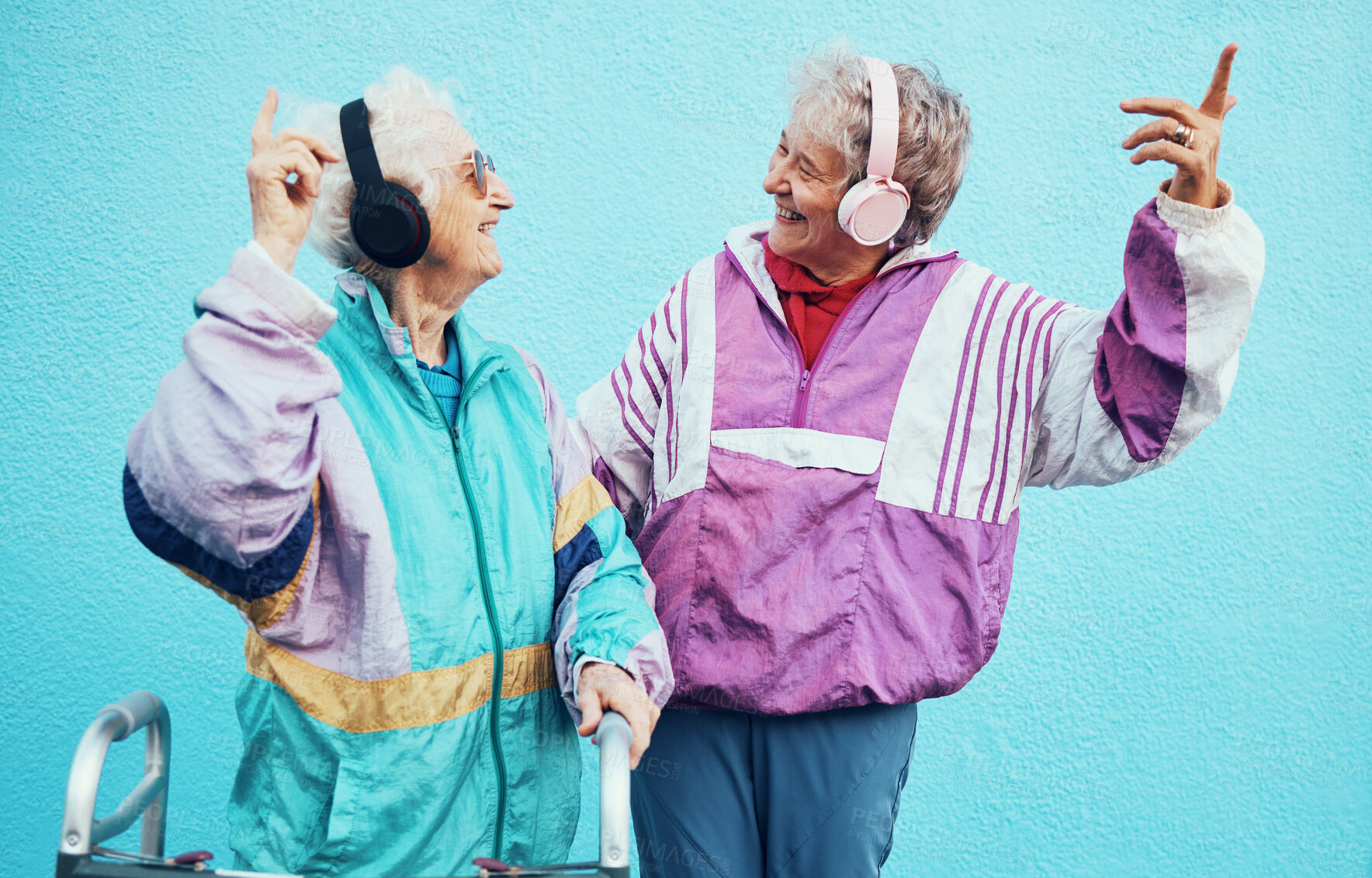 Buy stock photo Friends, city and senior women with headphones on blue background wall listening to audio, music and radio. Fashion, style and elderly females enjoy retirement, freedom and dancing in urban town