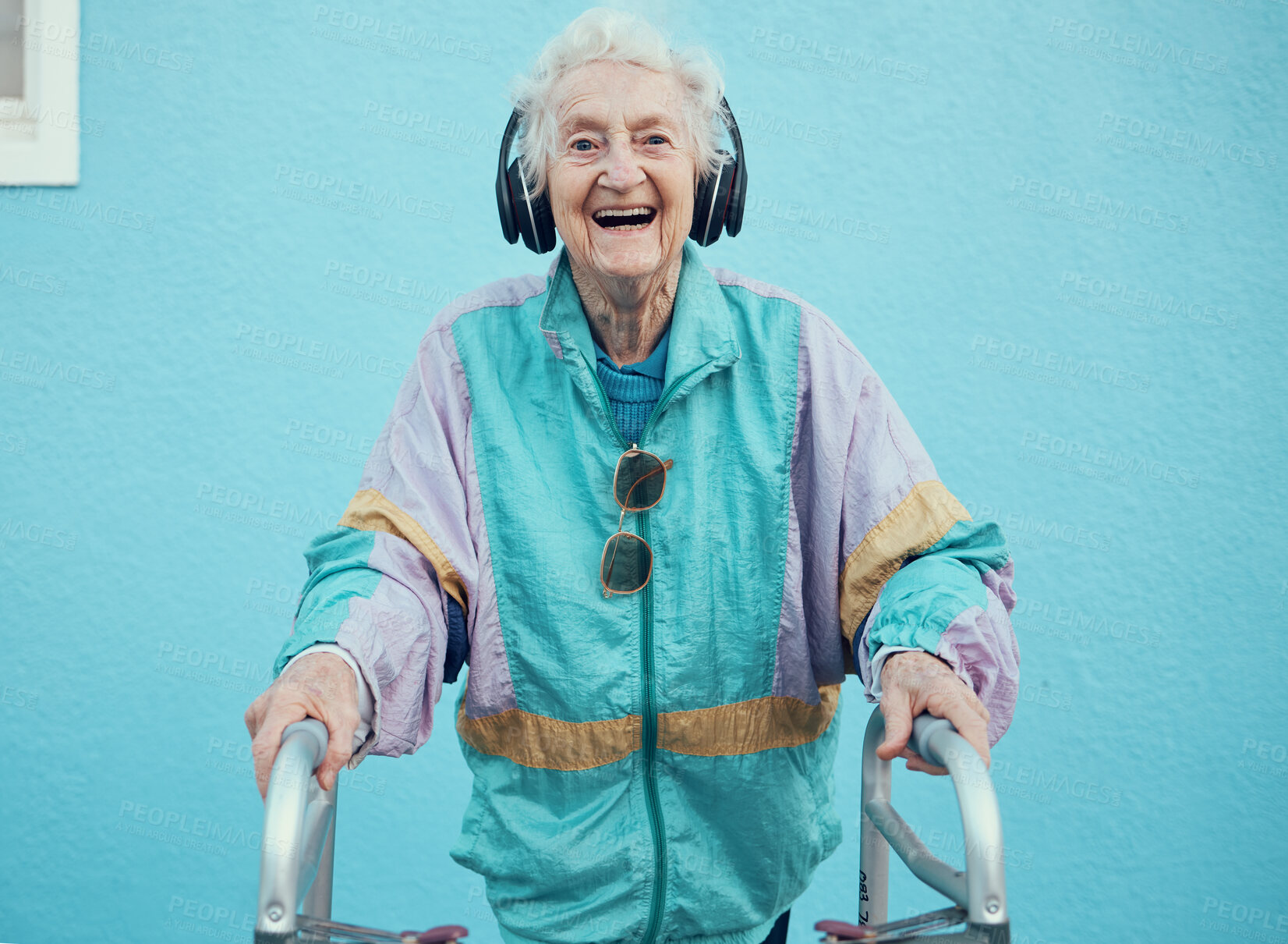 Buy stock photo Portrait, hip hop and old woman streaming music, radio or audio with freedom in a cool jacket and headphones. Smile, fashion and happy senior person listening to a song with a blue wall background