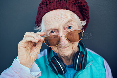 Buy stock photo Senior woman, face and fashion sunglasses, vintage and  90s clothes, cool style and headphones with attitude against a wall outdoor. Elderly model, edgy attitude and retro portrait or retirement