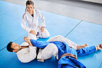 Karate, personal trainer and self defense training in the dojo for physical protection or health and safety. Black belt sensei man teaching woman to defend herself in a fight or combat at the gym