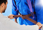 Coach, help and tie martial arts belt in dojo in graduation, progress or promotion to new class. Mentor, sensei and success with student in gym, helping from brown to purple level, karate or learning