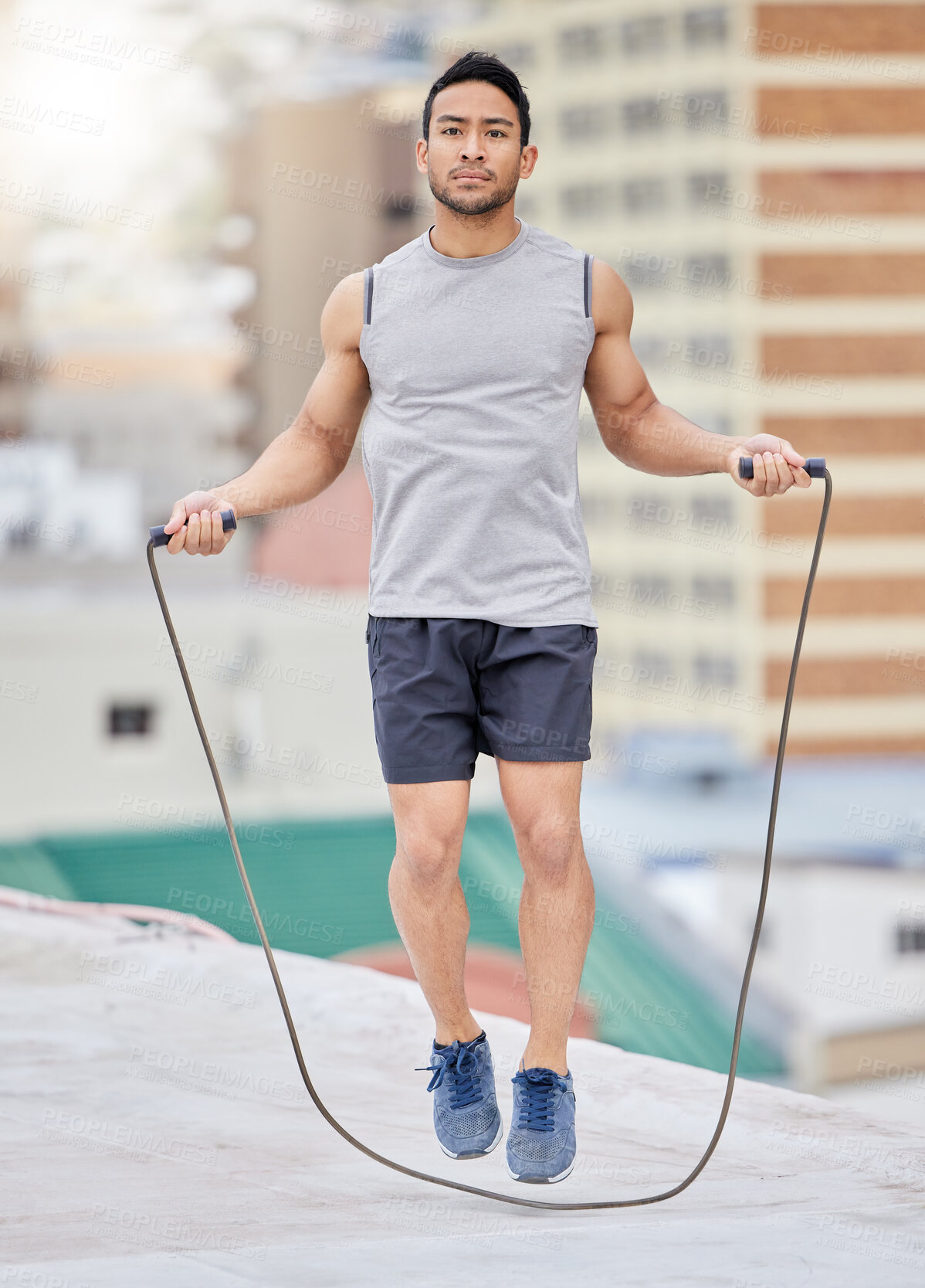 Buy stock photo Jump, rope and man on a rooftop for fitness training, exercise and skipping for cardio in the city. Jumping, focus and Asian athlete with energy for an urban workout for wellness, body and health