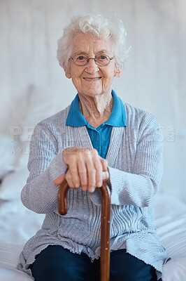 Buy stock photo Elderly woman, sitting portrait and smile on bed with happiness, walking stick and relax in nursing home. Happy senior lady, bedroom and cane for support, healthcare and wellness in retirement house