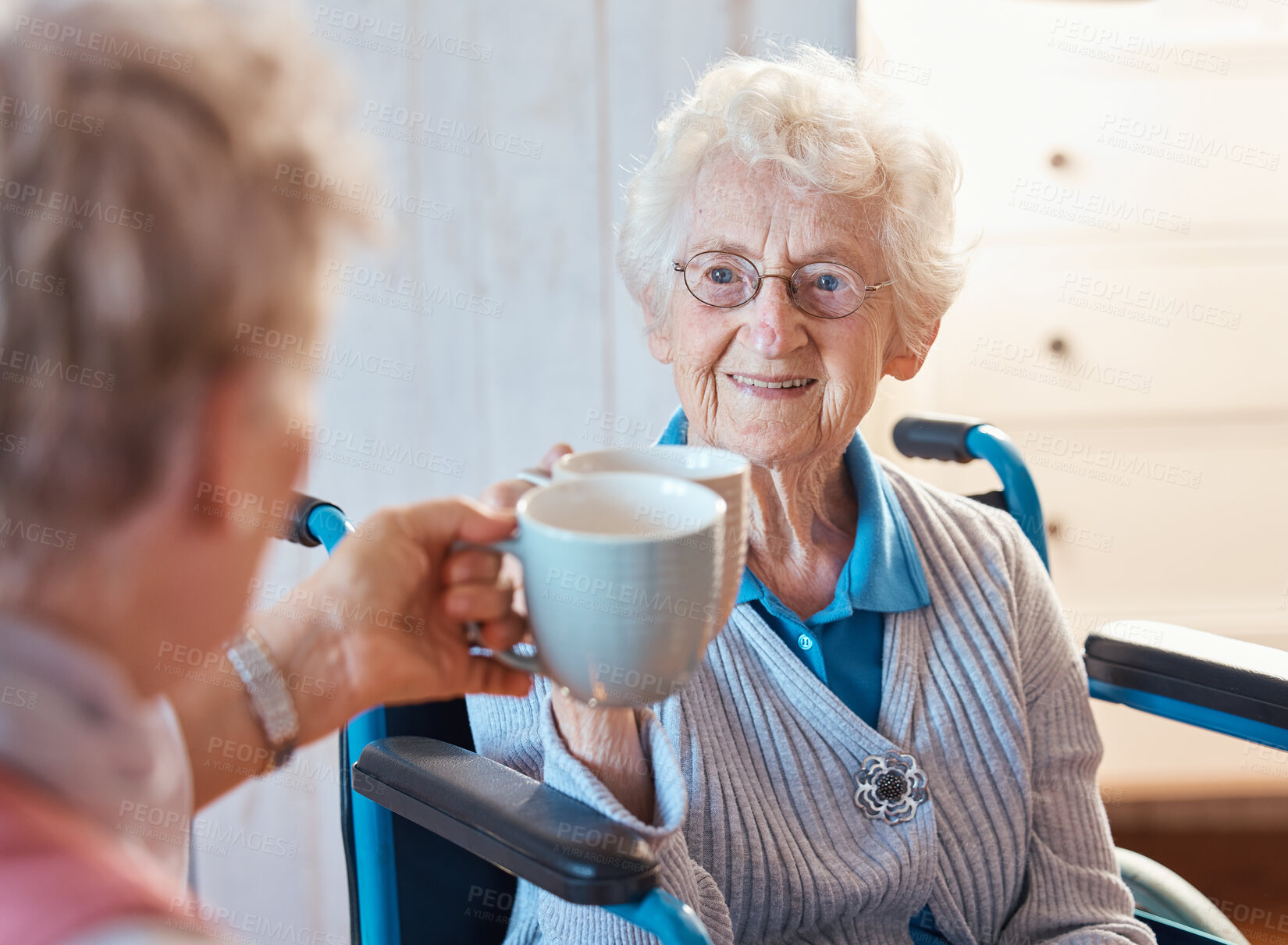 Buy stock photo Senior woman, happy friends and toast coffee in wheelchair in room, house or nursing home together. Elderly women, mug and smile for love, bonding and care in home with disability with happiness