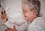 Smile, phone and senior woman in bed, text and read social media, message and relax in her home. Happy, elderly lady and online communication after wake up, browse and email on smartphone in bedroom