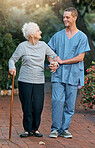 Nurse, senior woman and walking in park for healthcare and wellness. Physiotherapy, rehabilitation and retired elderly female with disability and cane talking to medical worker outdoors in garden.