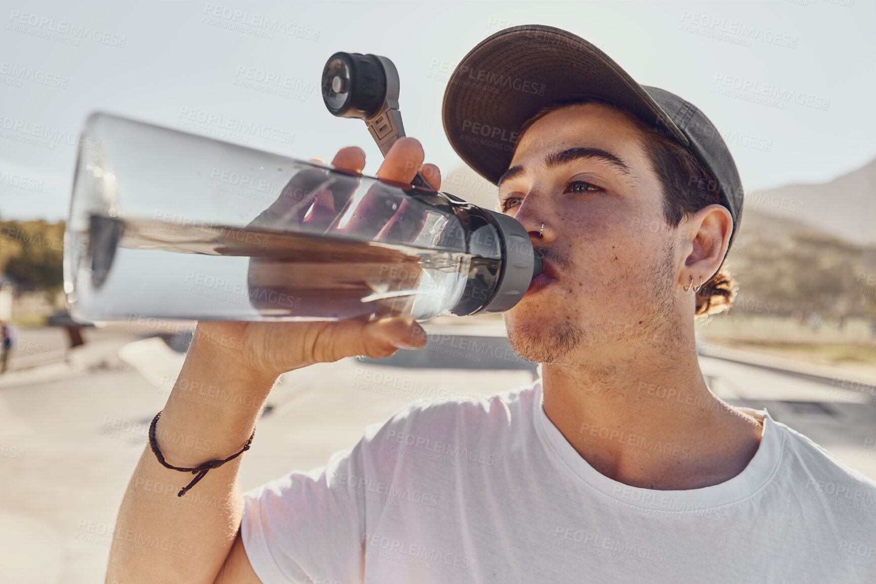 Buy stock photo Man, water bottle and outdoor closeup for hydration, fitness and workout in summer sunshine. Guy, drinking and water for exercise, training and wellness on break, relax or rest in urban park in sun