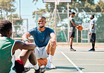 Basketball, team sports and social conversation at the court for break after fitness, training or exercise match. Happy basketball players talking, discussion or relaxing on the basketball court