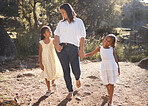 Mother and children holding hands while walking in nature on adventure, hiking or family bonding trip on mothers day. Woman outdoor at park for travel with daughters or girl kids for love and support