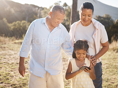 Buy stock photo Phone, family and nature with a girl and grandparents outdoor together during summer vacation. Social media, love and care with a senior man and woman bonding with their female grandchild outside