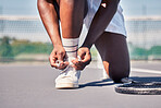 Sports, tennis and man tie shoes before game start, competition or fitness exercise on outdoor tennis court. Wellness health, ground and legs of African player prepare for workout, training or cardio